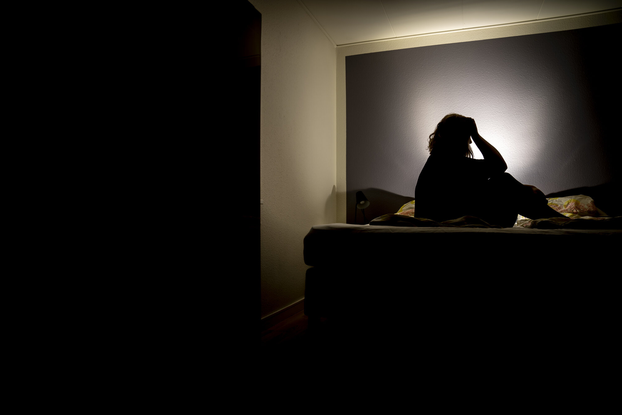 Illustrasjon av en person som sitter i mørket og har det vondt