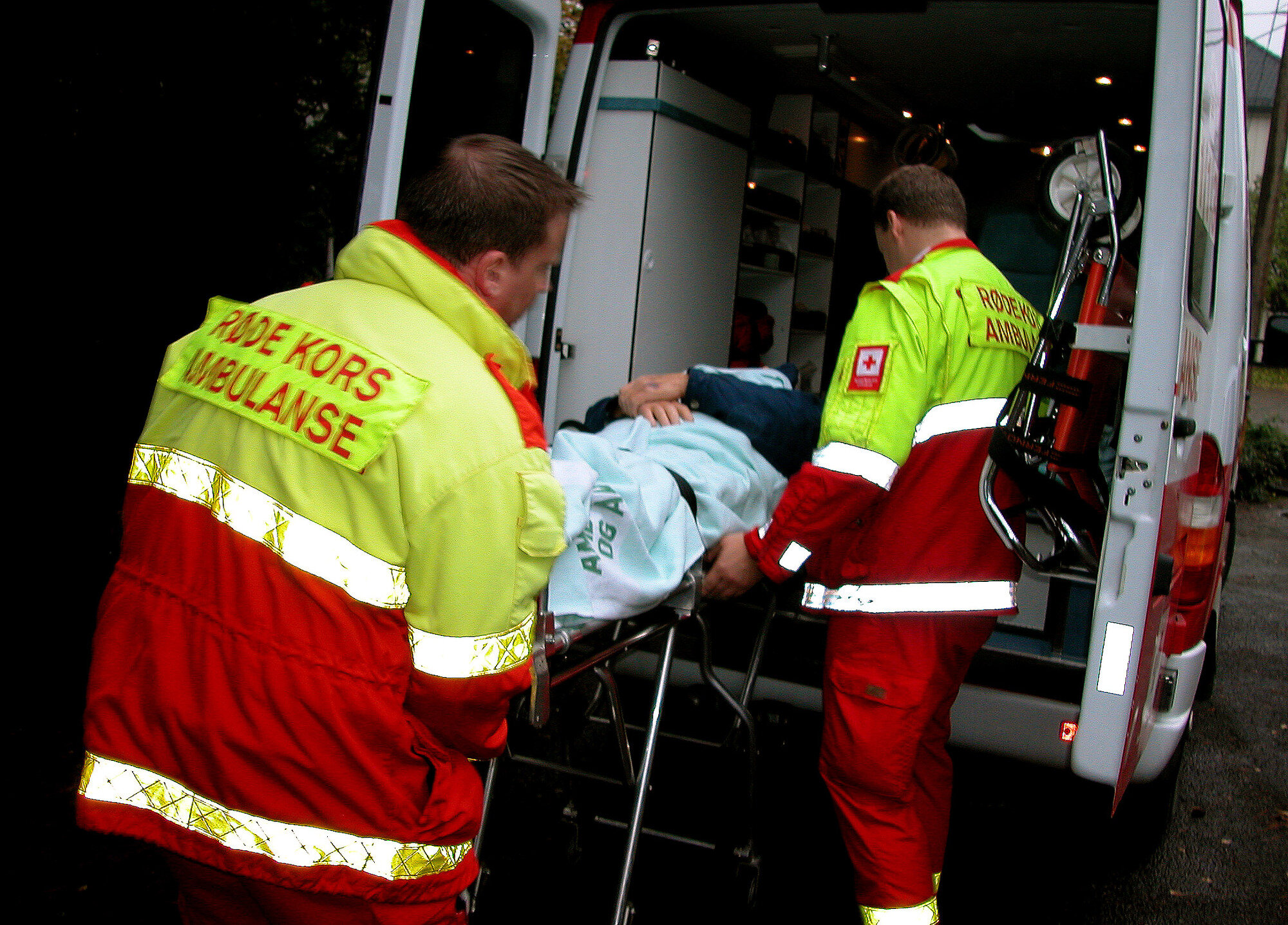 Bildet viser en mann som blir hentet av ambulansepersonale, og ligger på båre.