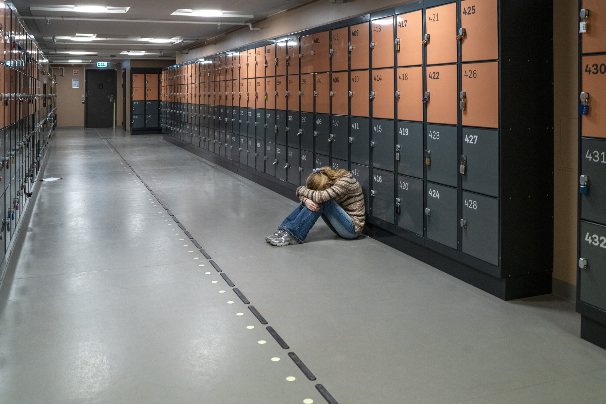 Bildet viser en ungdom som sitter i en korridor