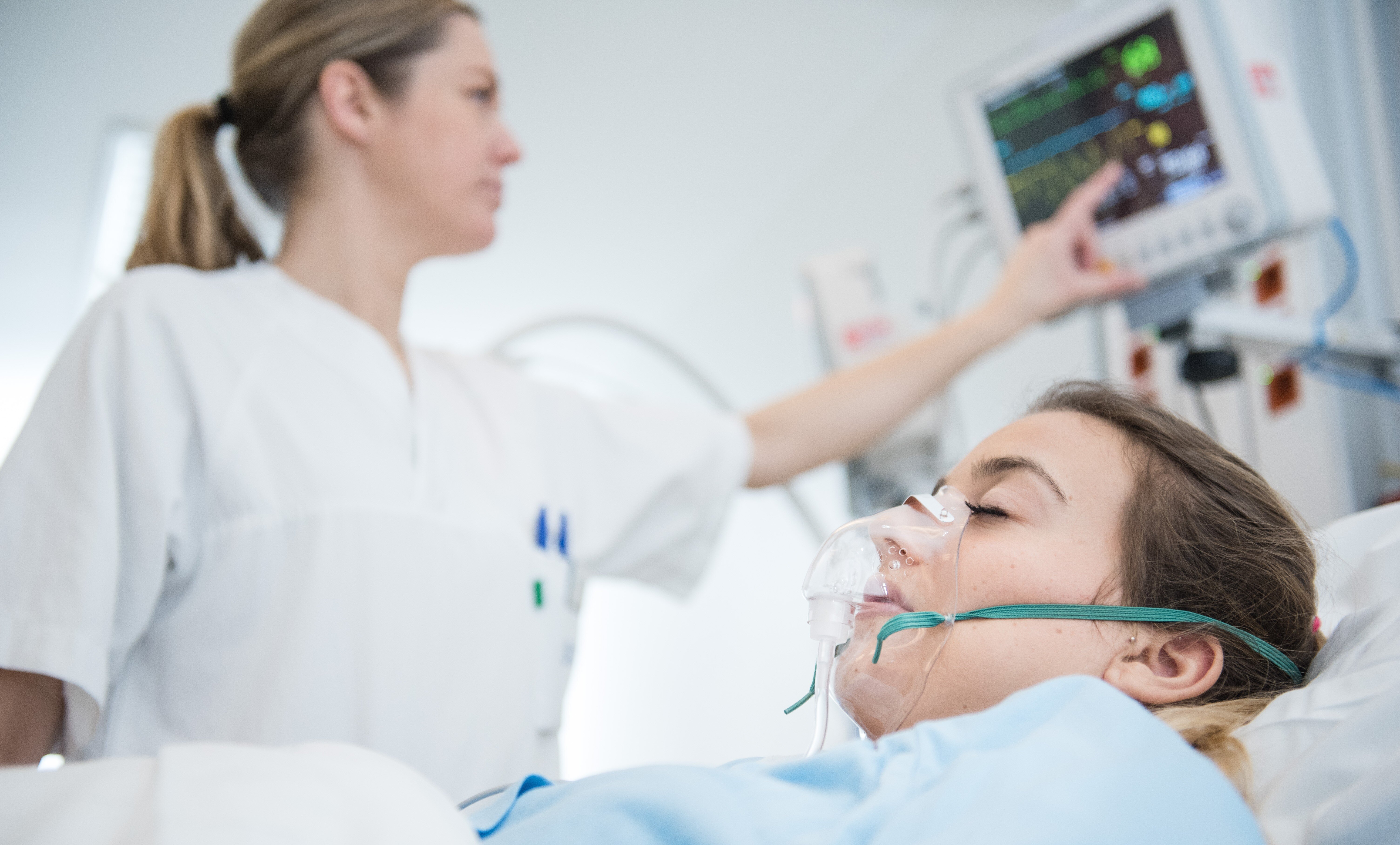 Bildet viser en sykepleier som pleier en pasient i sengen