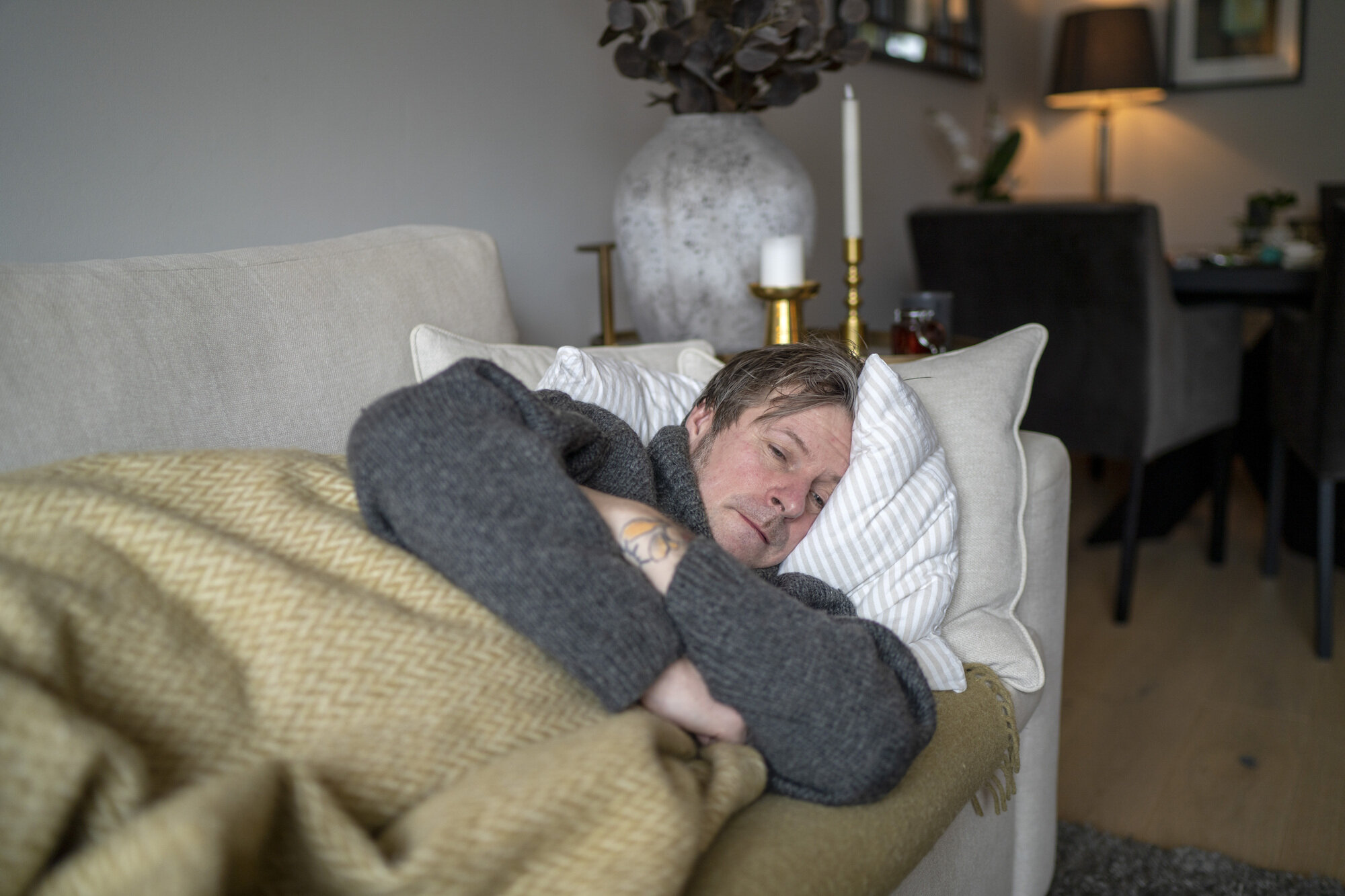 Bildet viser en mann som ligger på sofaen og er syk.