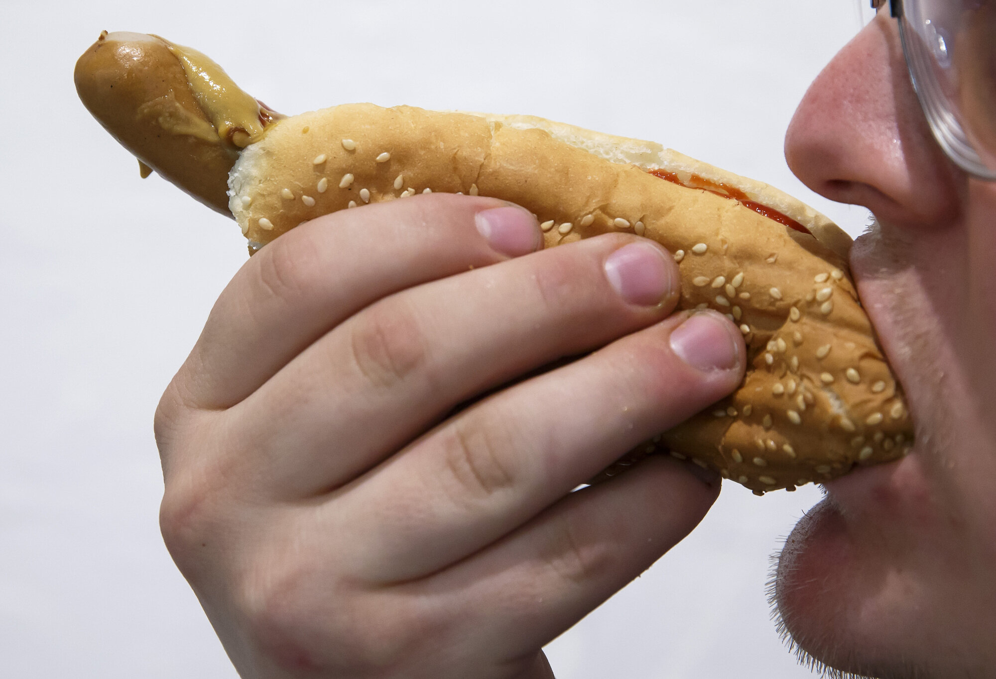 Bildet viser en mann som spiser en pølse i brød.