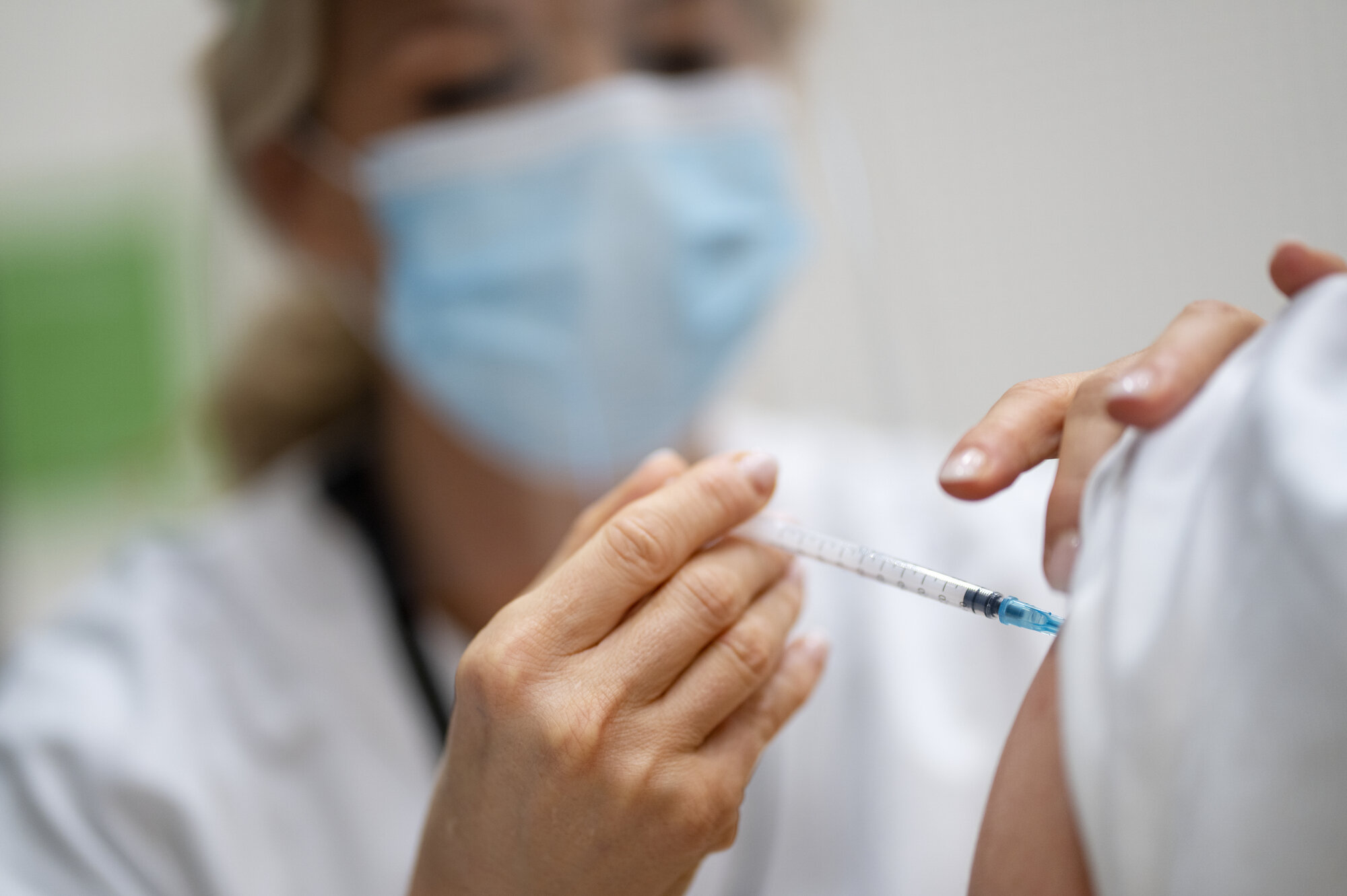 Bildet viser helsepersonell som setter en vaksine.