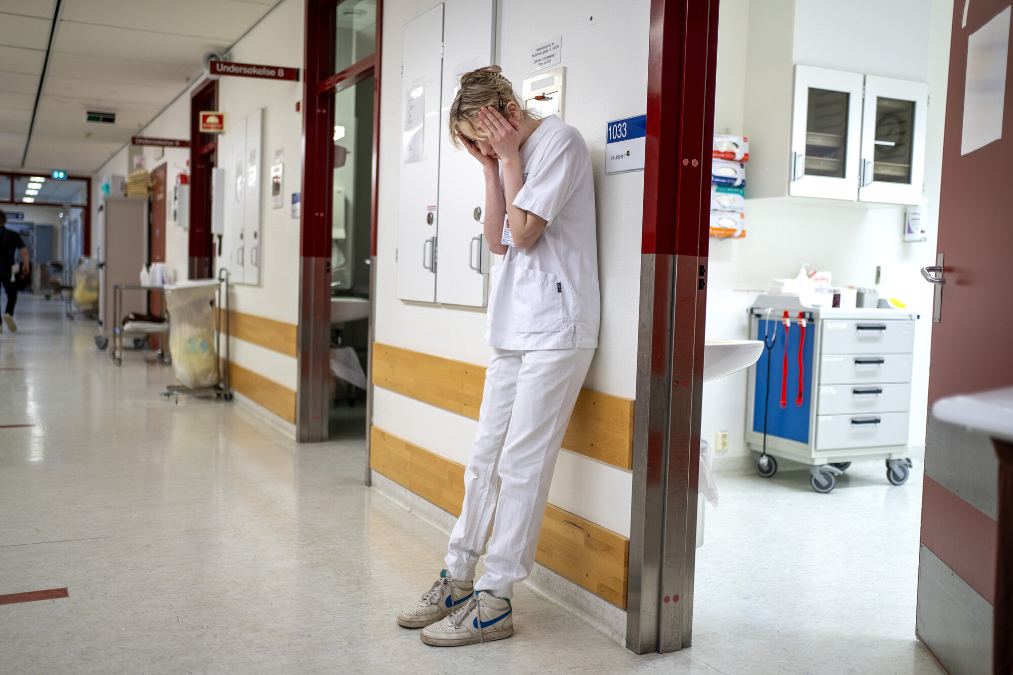 Bilde av sliten sykepleier i sykehuskorridor