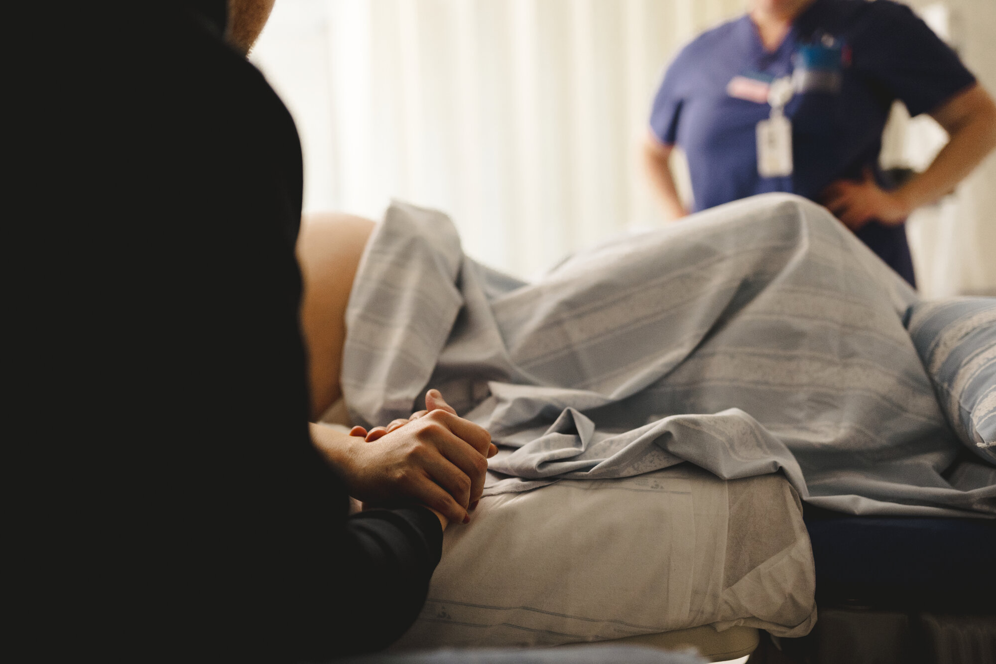 Bildet viser en kvinne som skal føde. I bakgrunnen: en jordmor.