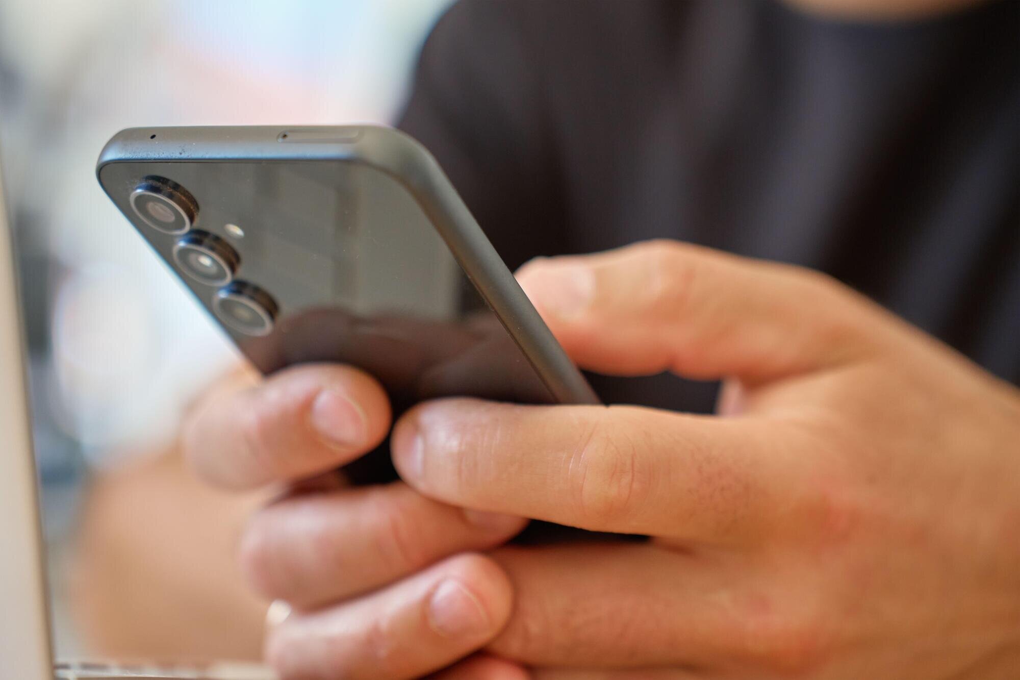 Bildet viser en mann som scroller på telefonen.