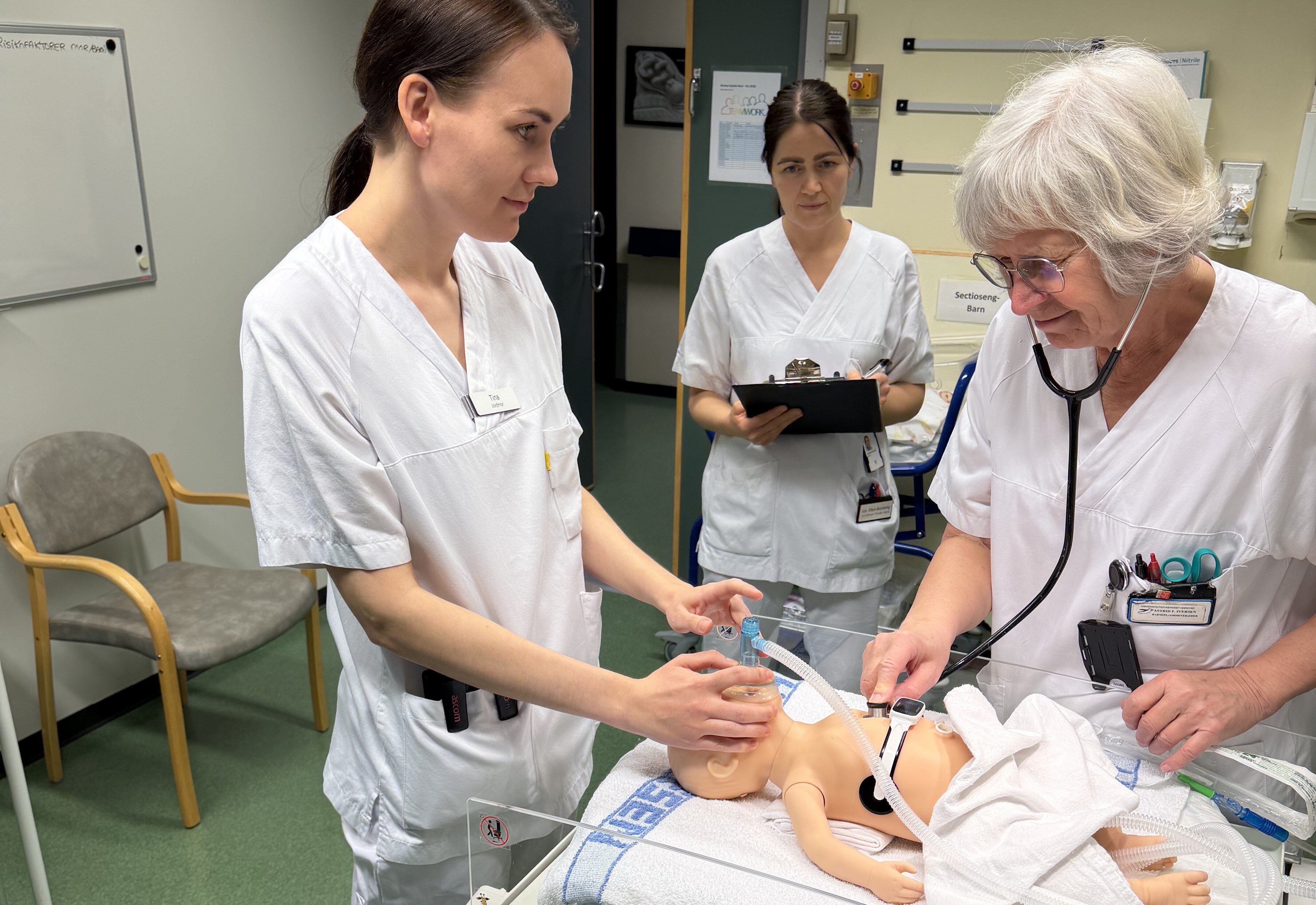 Bildet viser to jordmødre og en barnepleier som trener på nyfødtresuscitering på babydokke