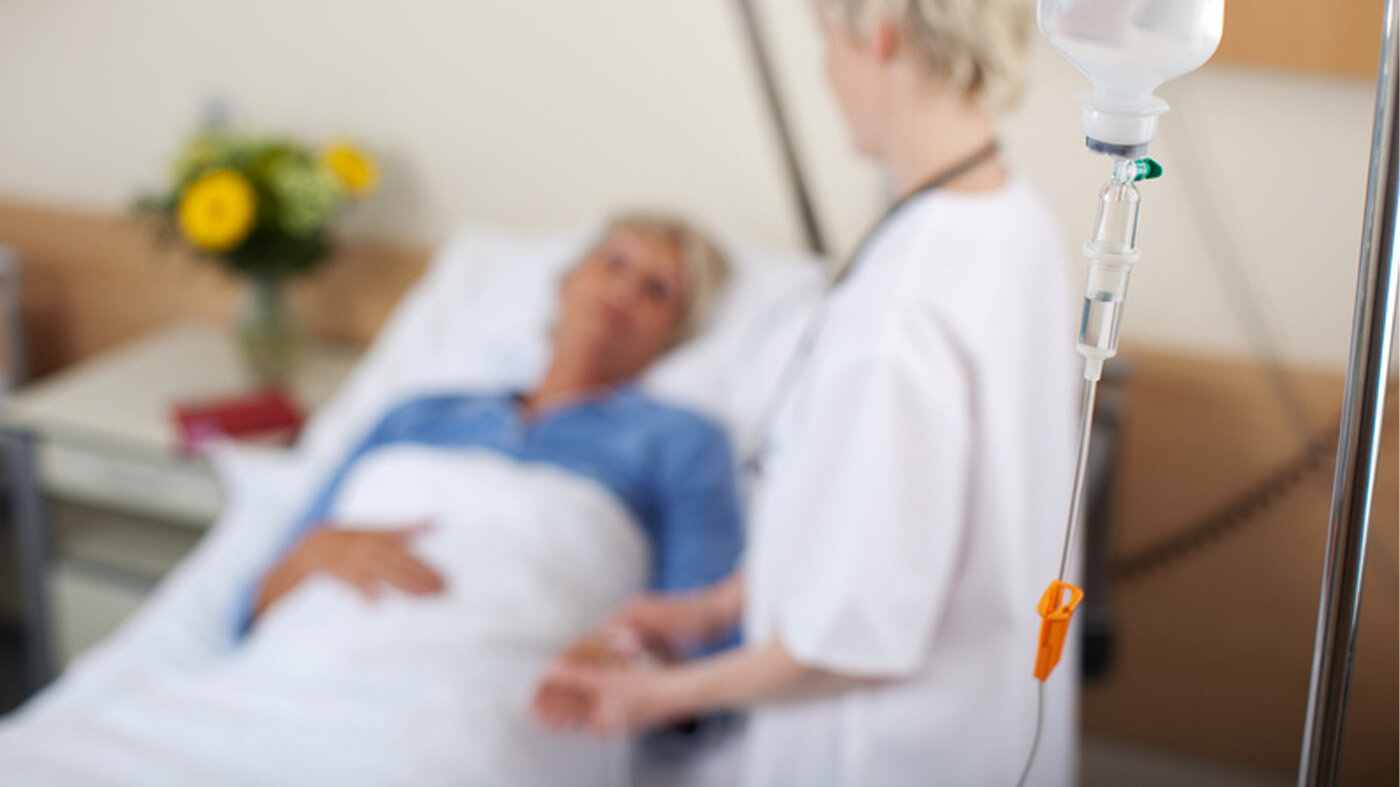 Bildet viser en sykepleier som står ved en pasient