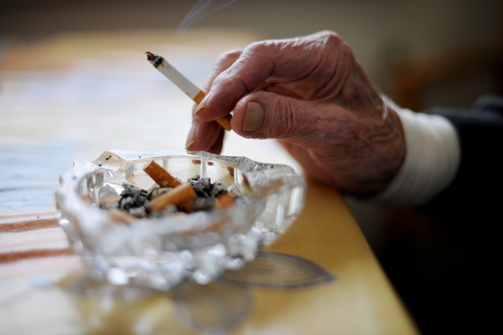 Bilde av hånd med sigarett over askebeger