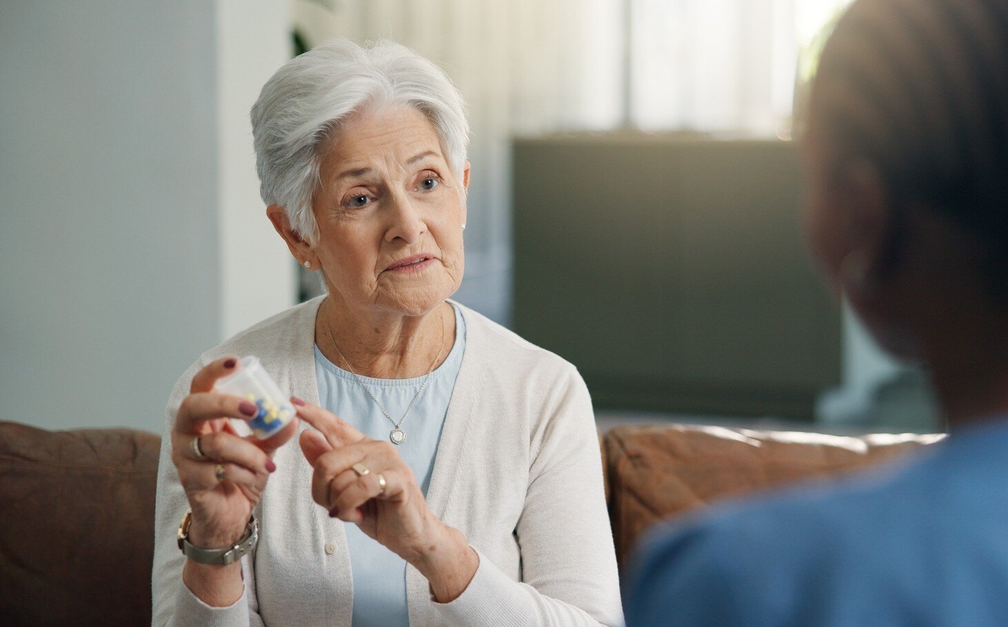 Bildet viser en kvinnelig pasient som tar medisiner med en sykepleier til stede