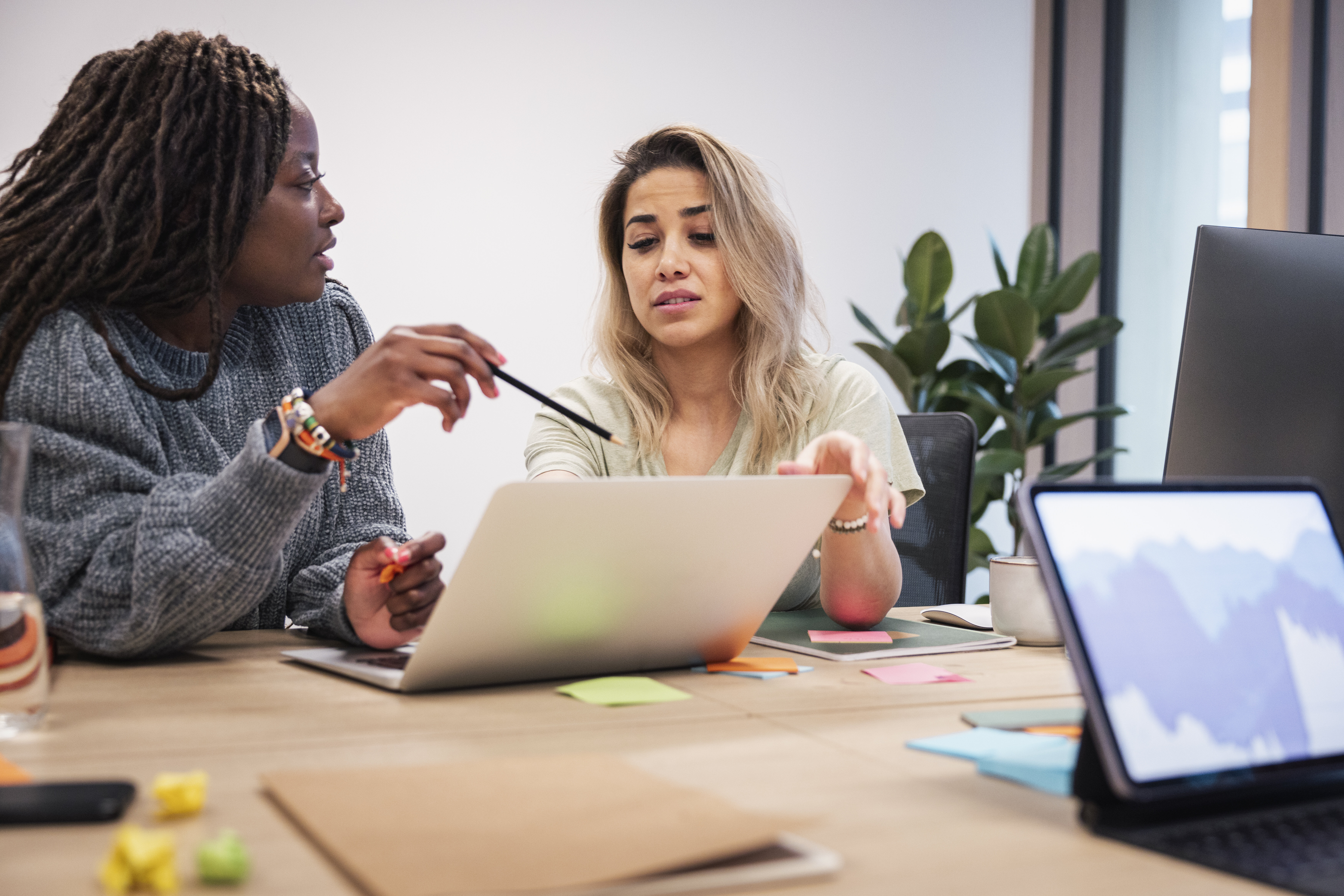 Helsesykepleier og skoleansatt diskuterer Bildet viser to kvinner som sitter og diskuterer foran en PC