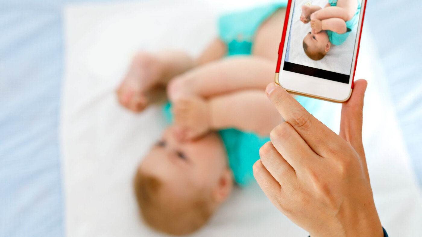 Noen tar bilde av en baby med mobiltelefonen. Noen tar bilde av en baby med mobiltelefonen.