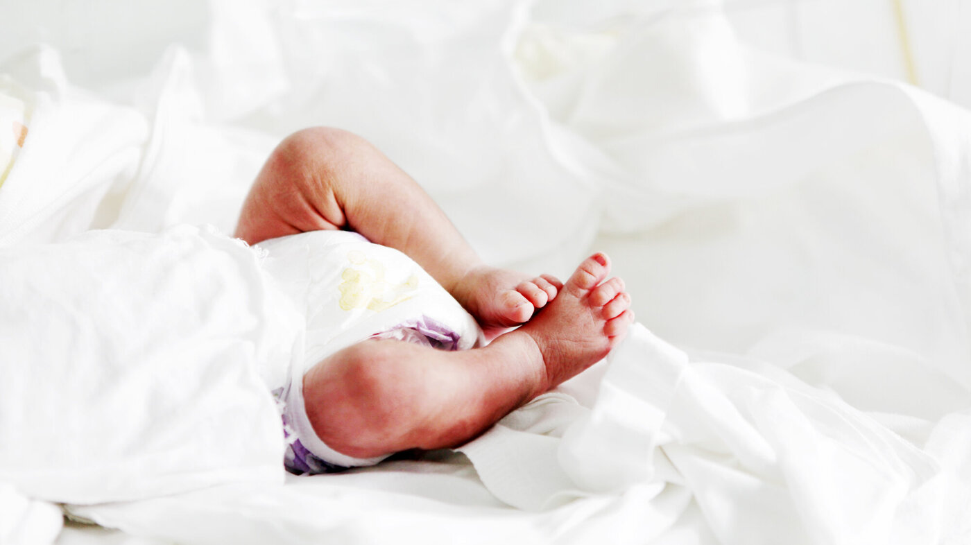Bildet viser underkroppen til en nyfødt som ligger i kuvøse.