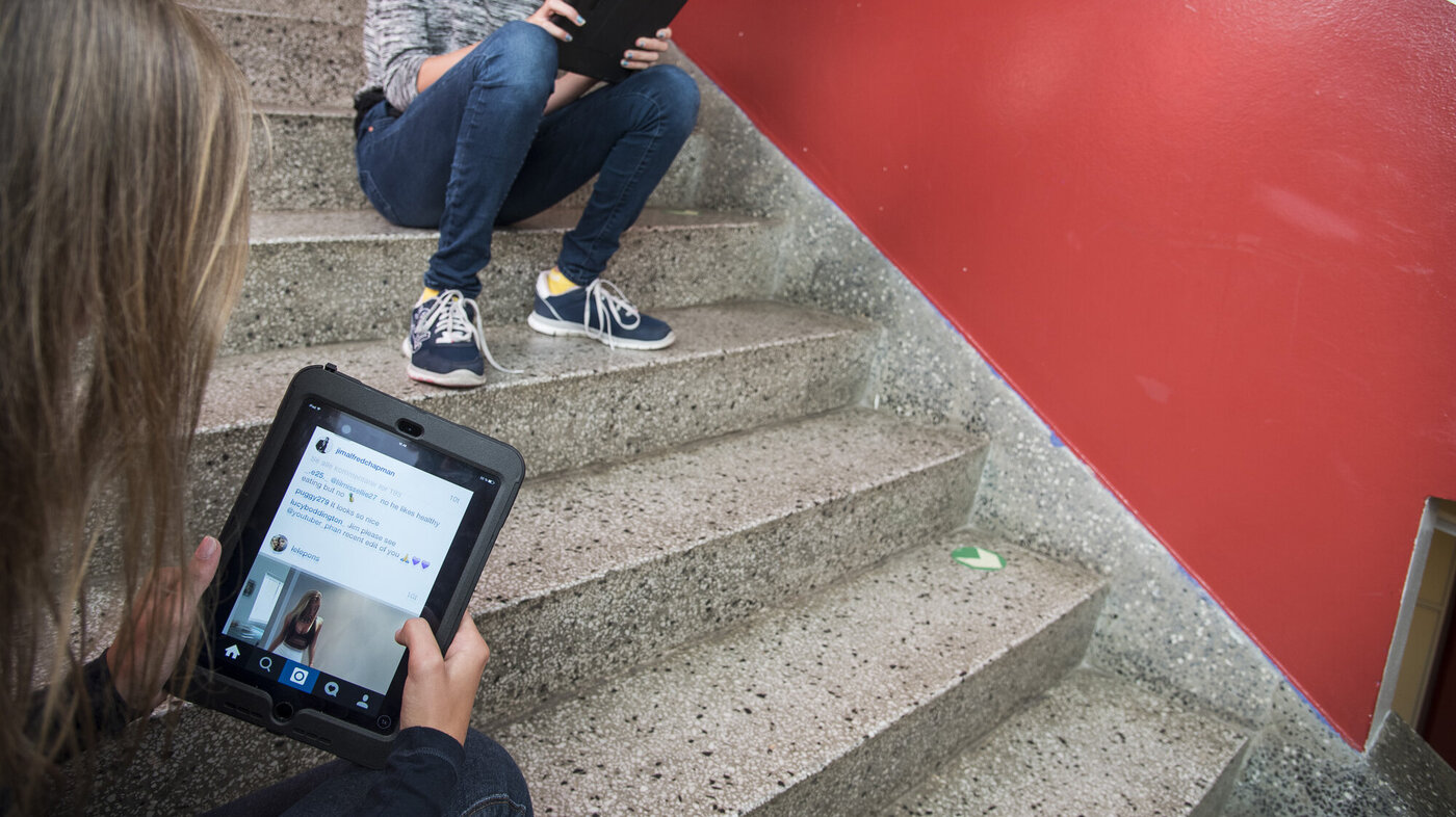 Elever sitter i en trapp og sjekker Instagram på iPad.