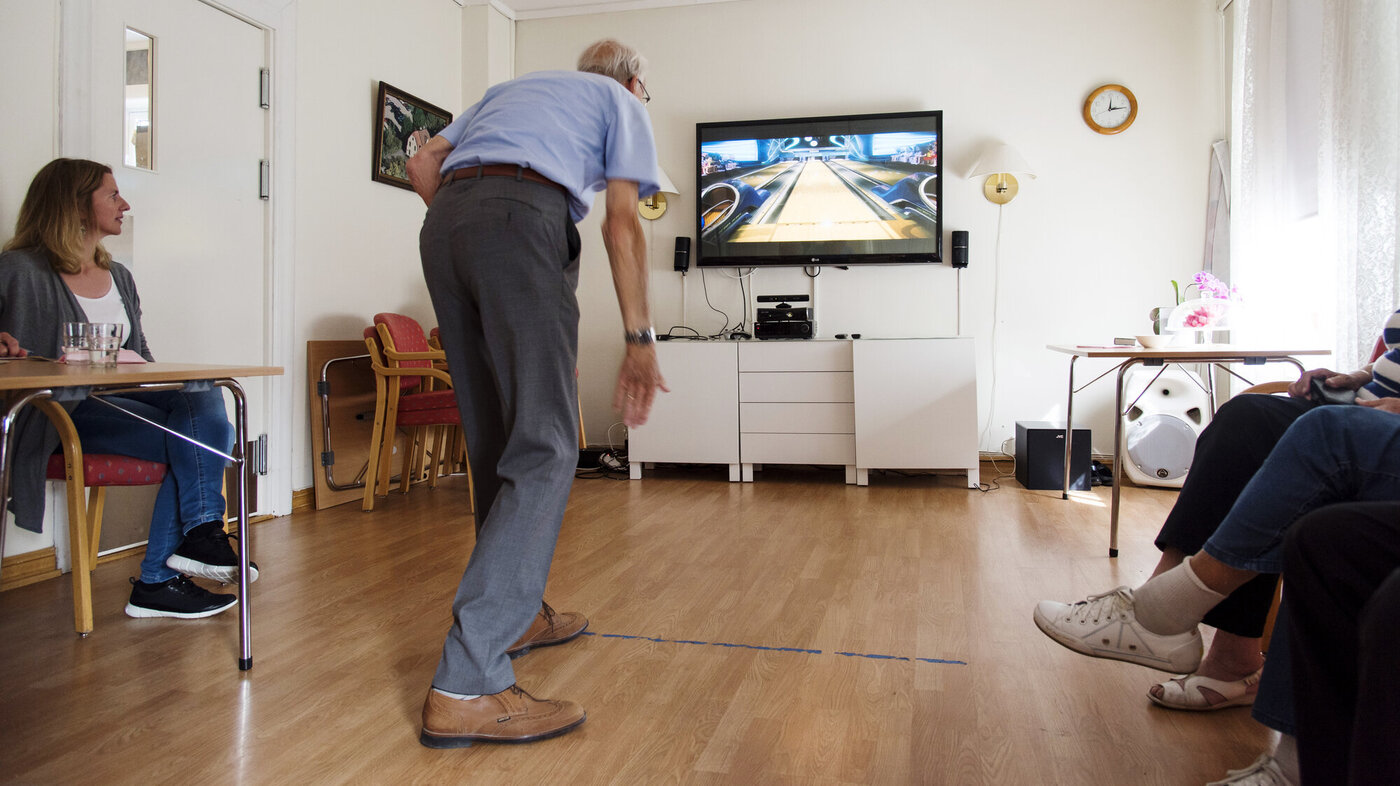 Bildet viser en eldre mann som spiller bowling på storskjerm ved hjelp av Kinect.
