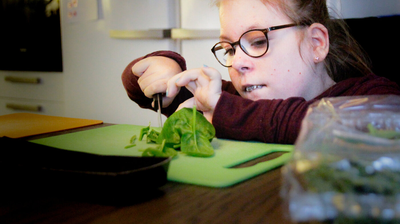 Bildet viser at Emma skjærer salat