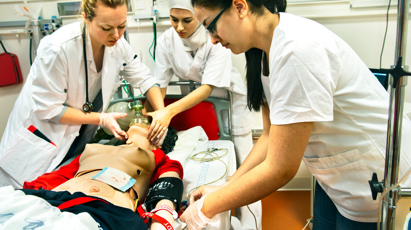 Sykepleier- og legestudenter øver på en akuttsituasjon med en dukke i sykesengen.
