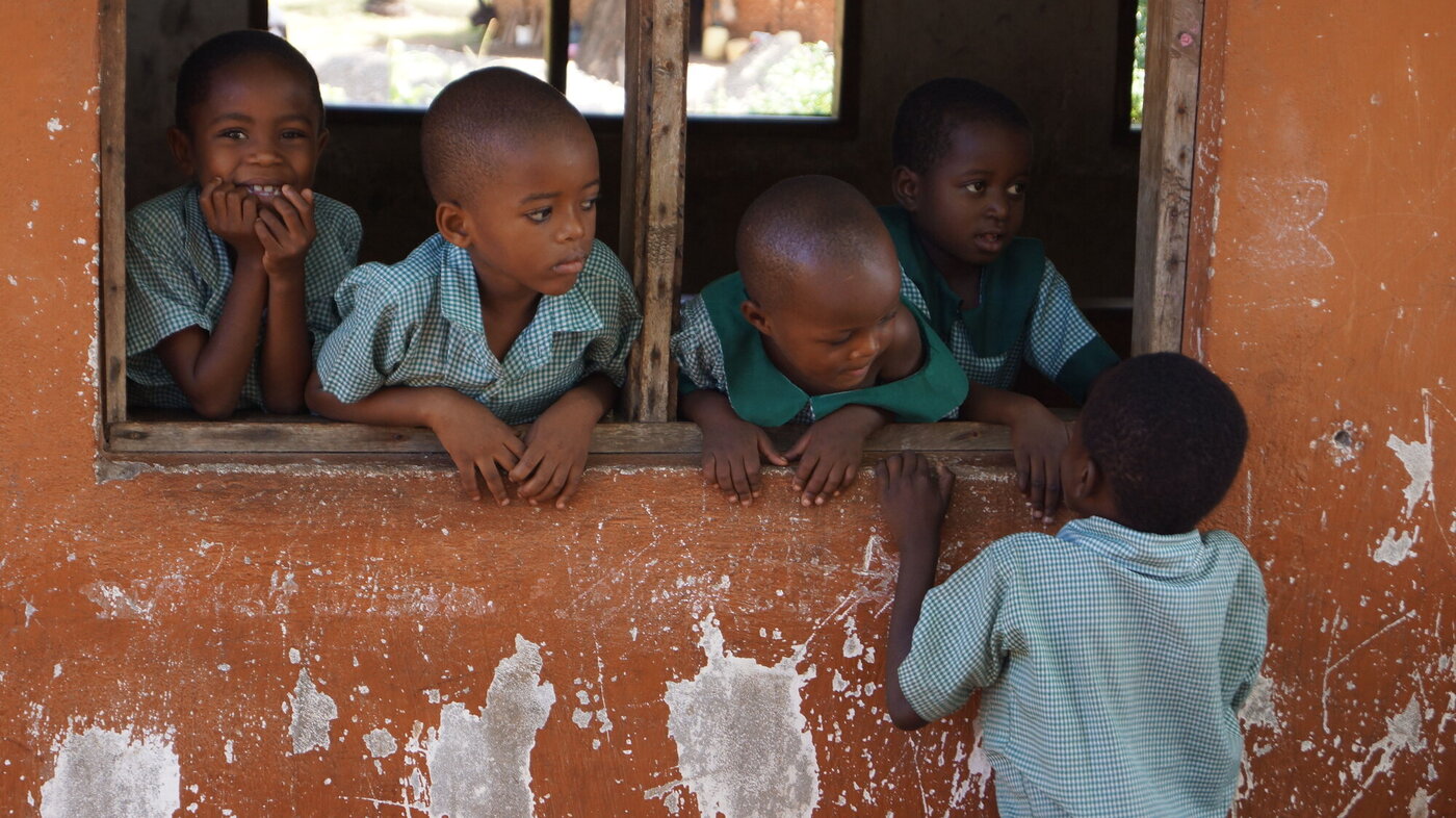 Afrikanske barn som står og ser ut gjennom et åpent vindu
