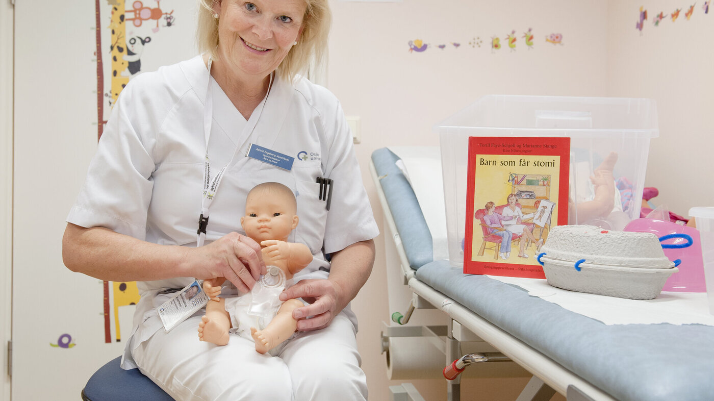 Bildet viser Astrid Ingeborg Austrheim som holder en dukke med pose på magen.