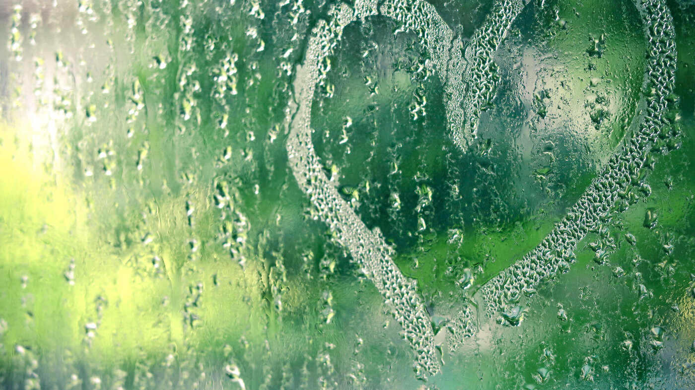 Bildet viser en vindusrute full av regndråper med et hjerte tegnet i regndråpene.