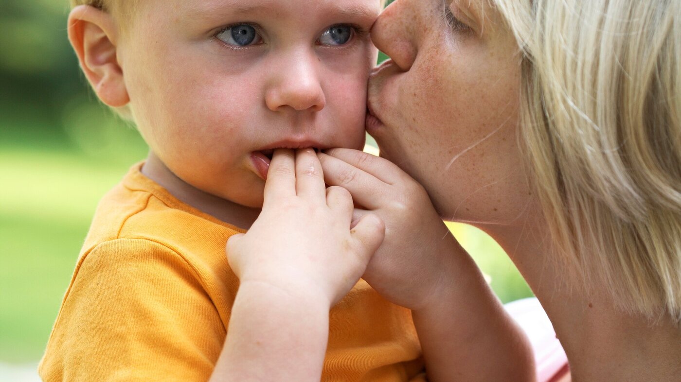 Bildet viser en liten gutt som gråter og som får kyss på kinnet av en kvinne til trøst.