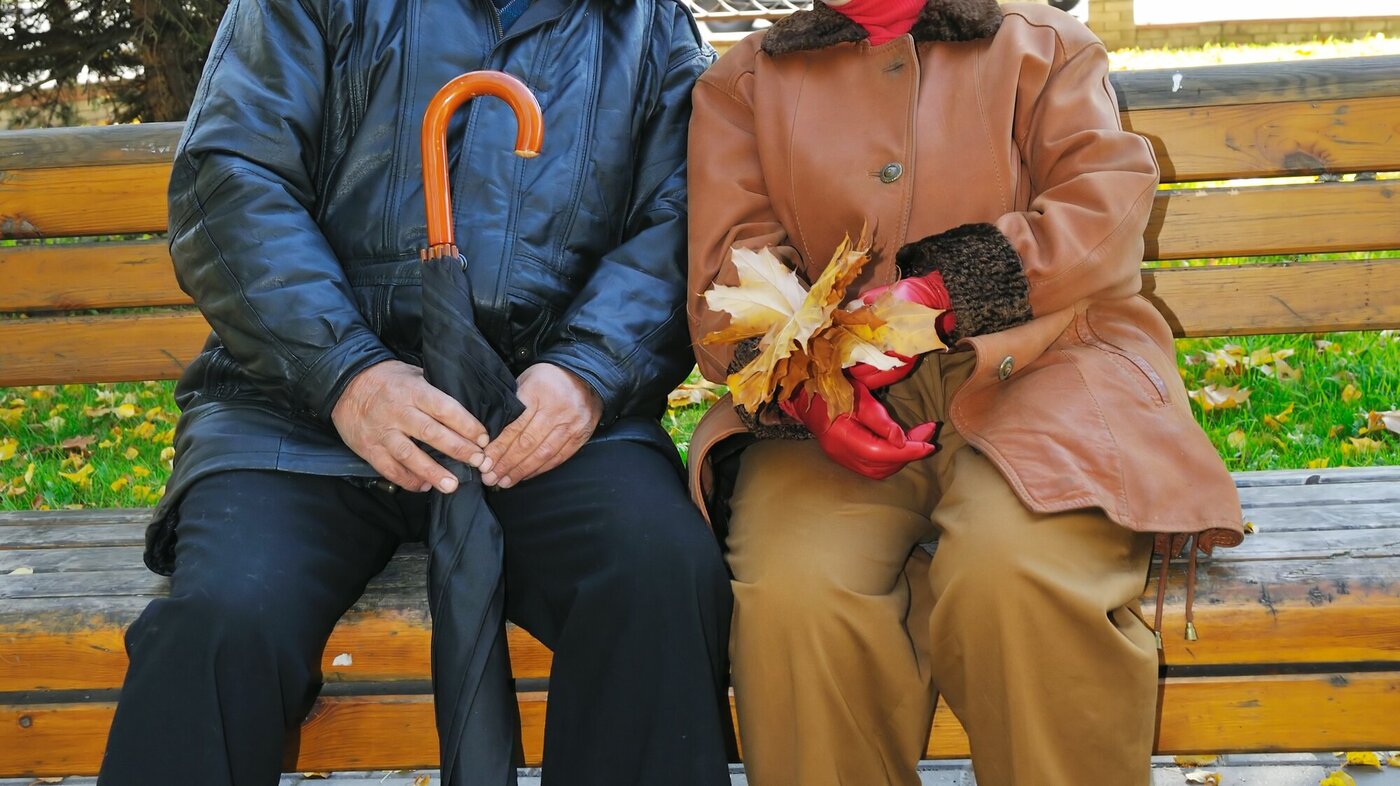 Bildet viser to eldre mennesker som sitter på en benk og ler.