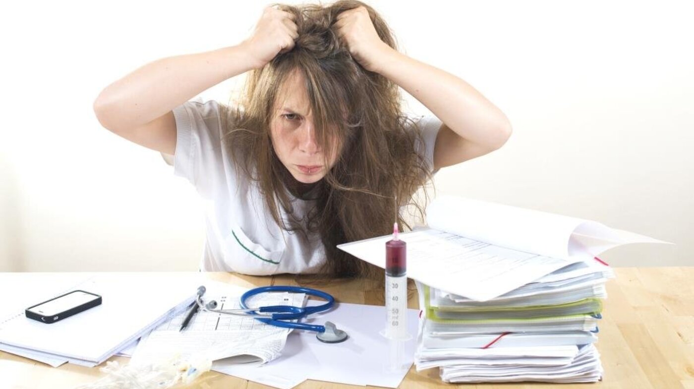 Bildet viser en frustrert sykepleier som river seg i håret.