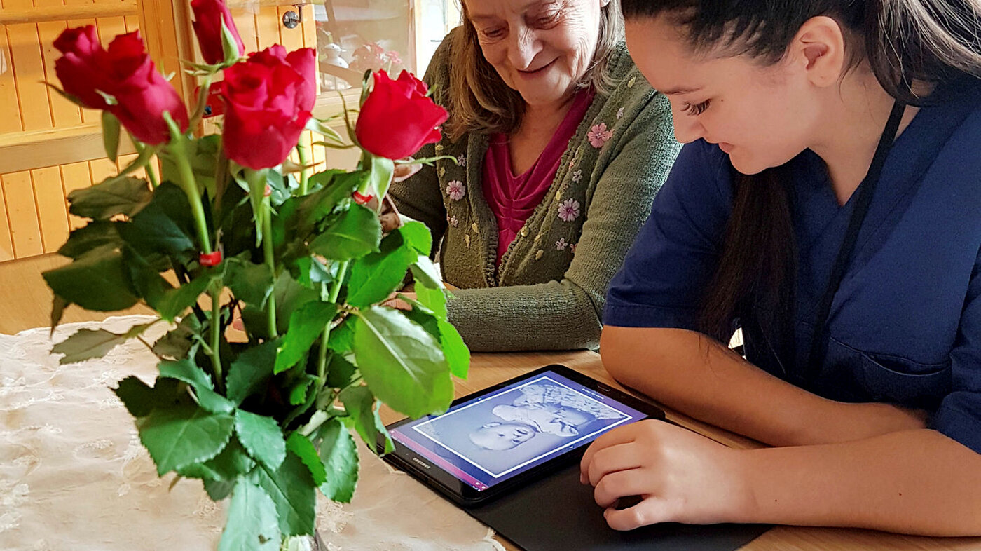 Lærling Tina Singh ser på bilder i appen Min Memoria sammen med beboer Kirsten ved Tiller helse- og velferdssenter i Trondheim 