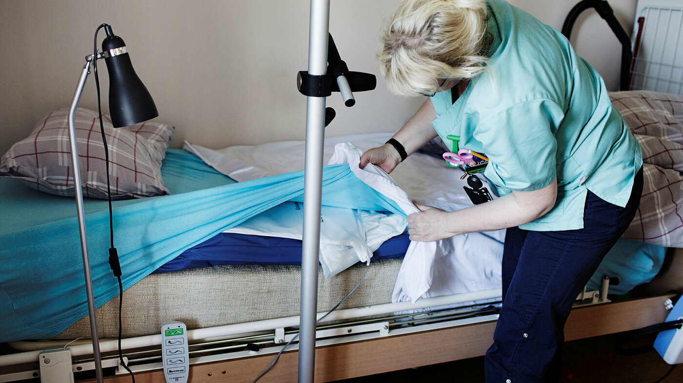 Bildet viser sykepleier i Selbu, Mariann Røset, som skifter sengetøy i en omsorgsbolig.