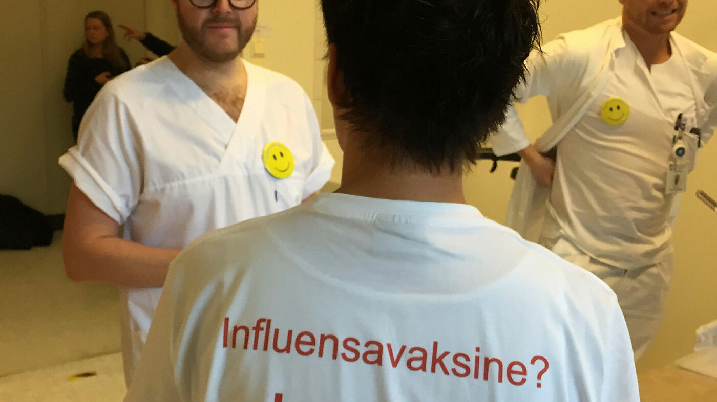 Bildet viser ryggen på en som har en t-skjorte med skriften Influensavaksine? Ja takk!