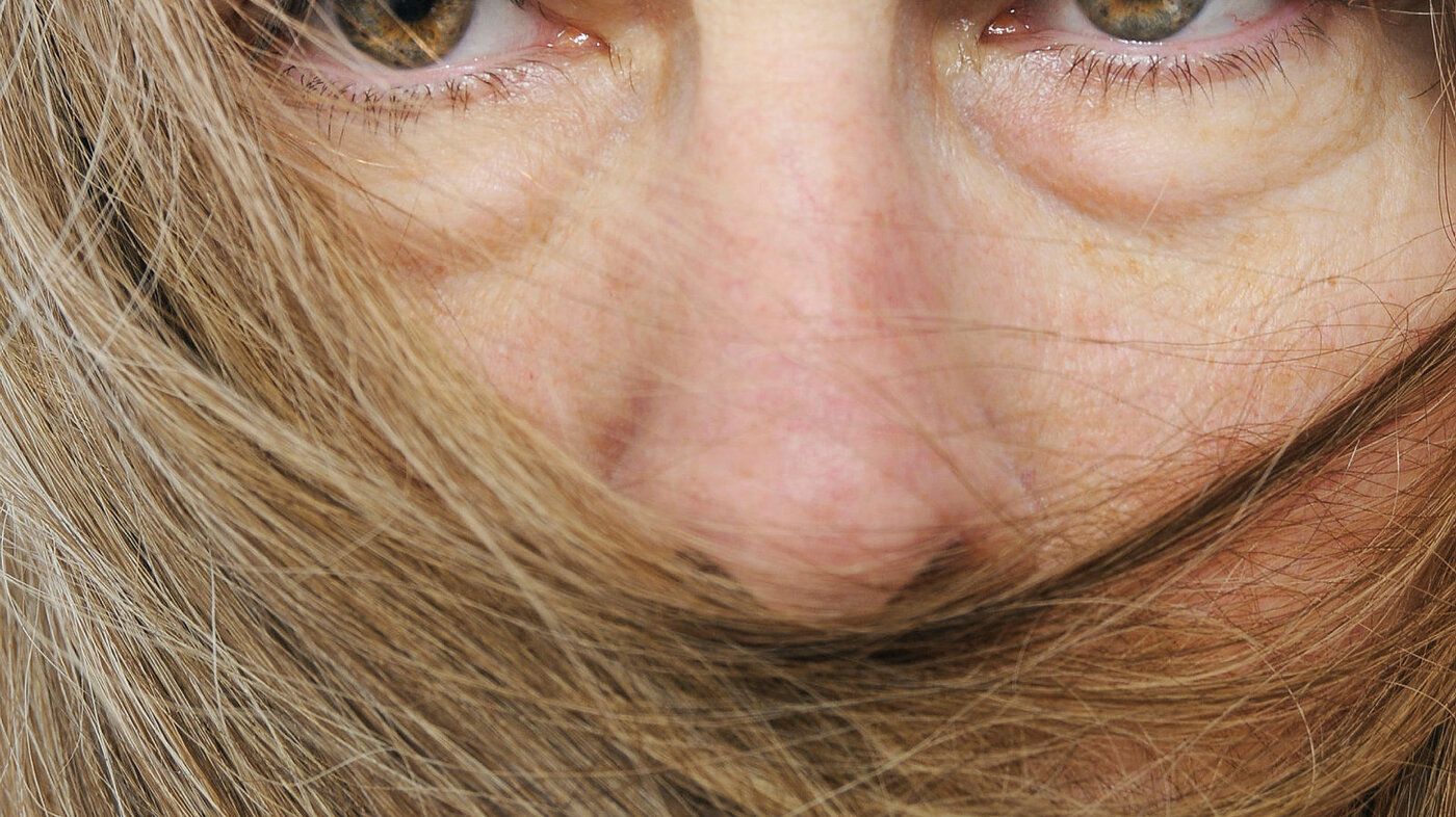 Nærbilde av kvinne med munnen dekket av hår.
