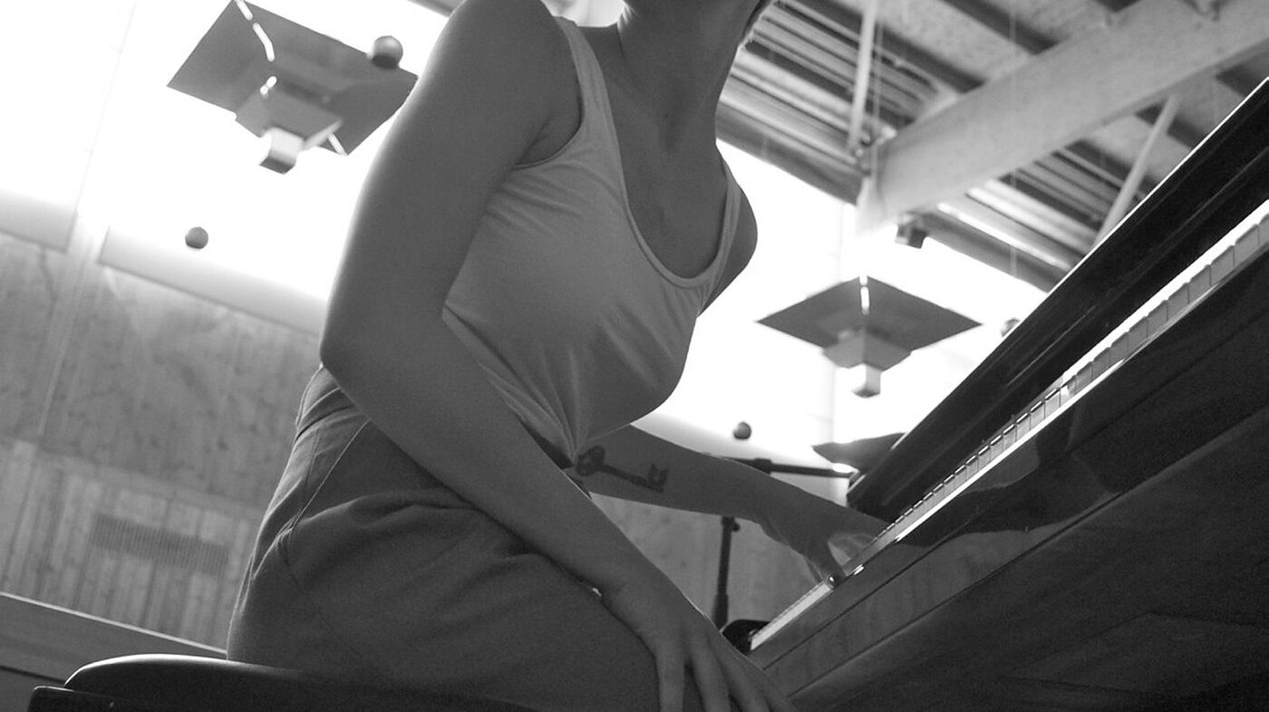 Bildet viser en ung kvinne som sitter ved et piano