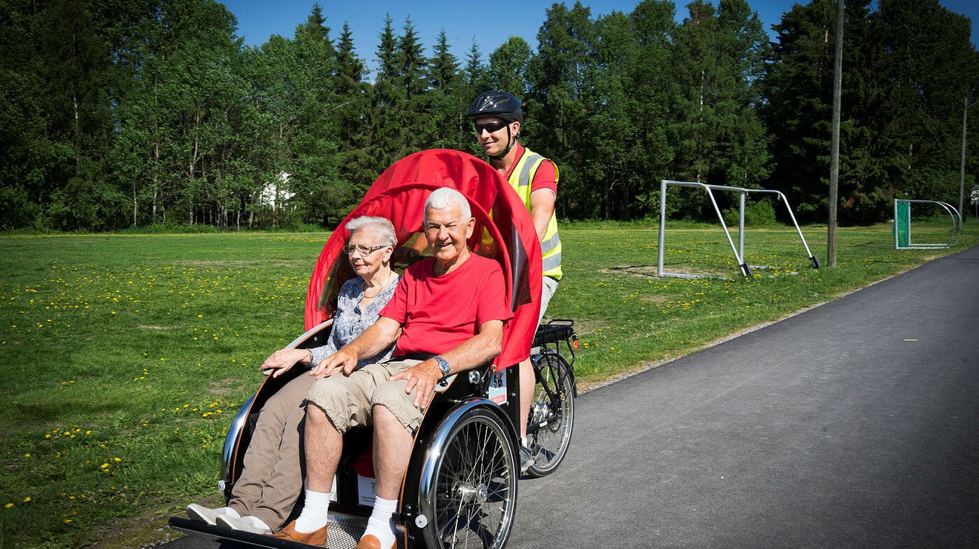 Bildet viser enhetsleder Håvard Lobben-Seth som sykler pasient Solveig Johansen og samboer Alf Krossli på besøk ved Gulset sykehjem i Skien.