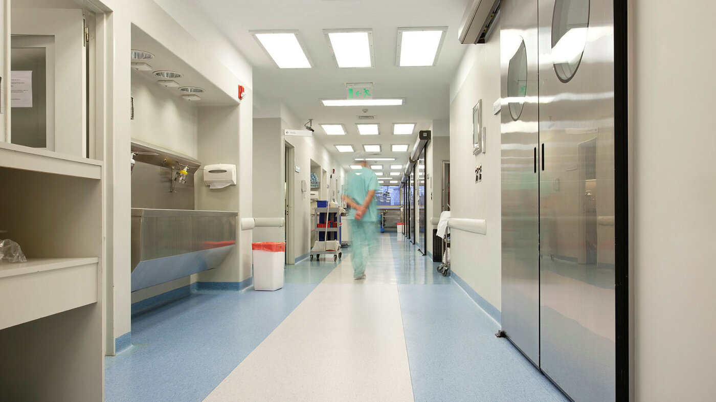 Helsepersonell som går bortover i en sykehuskorridor.