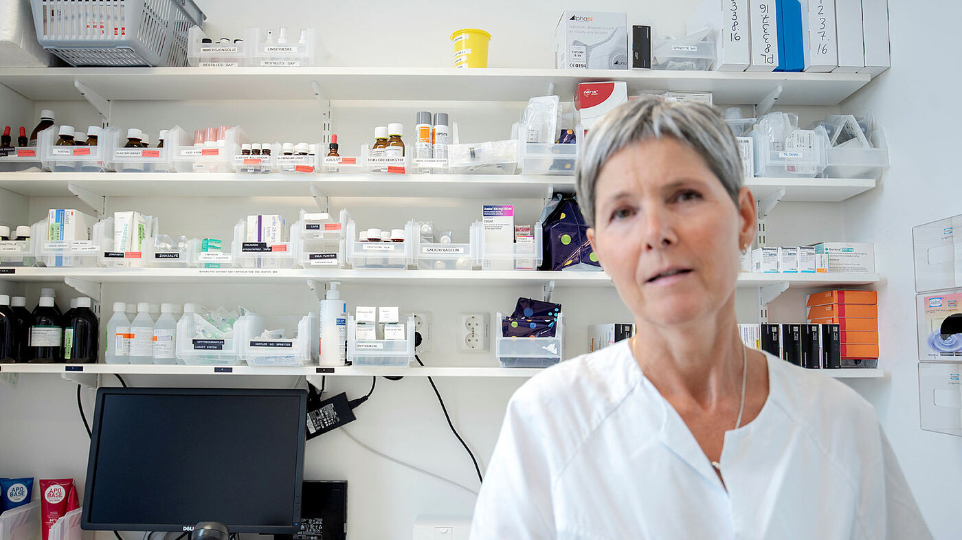 Bildet viser Ingrid Slørdal foran en hylle med medisiner.
