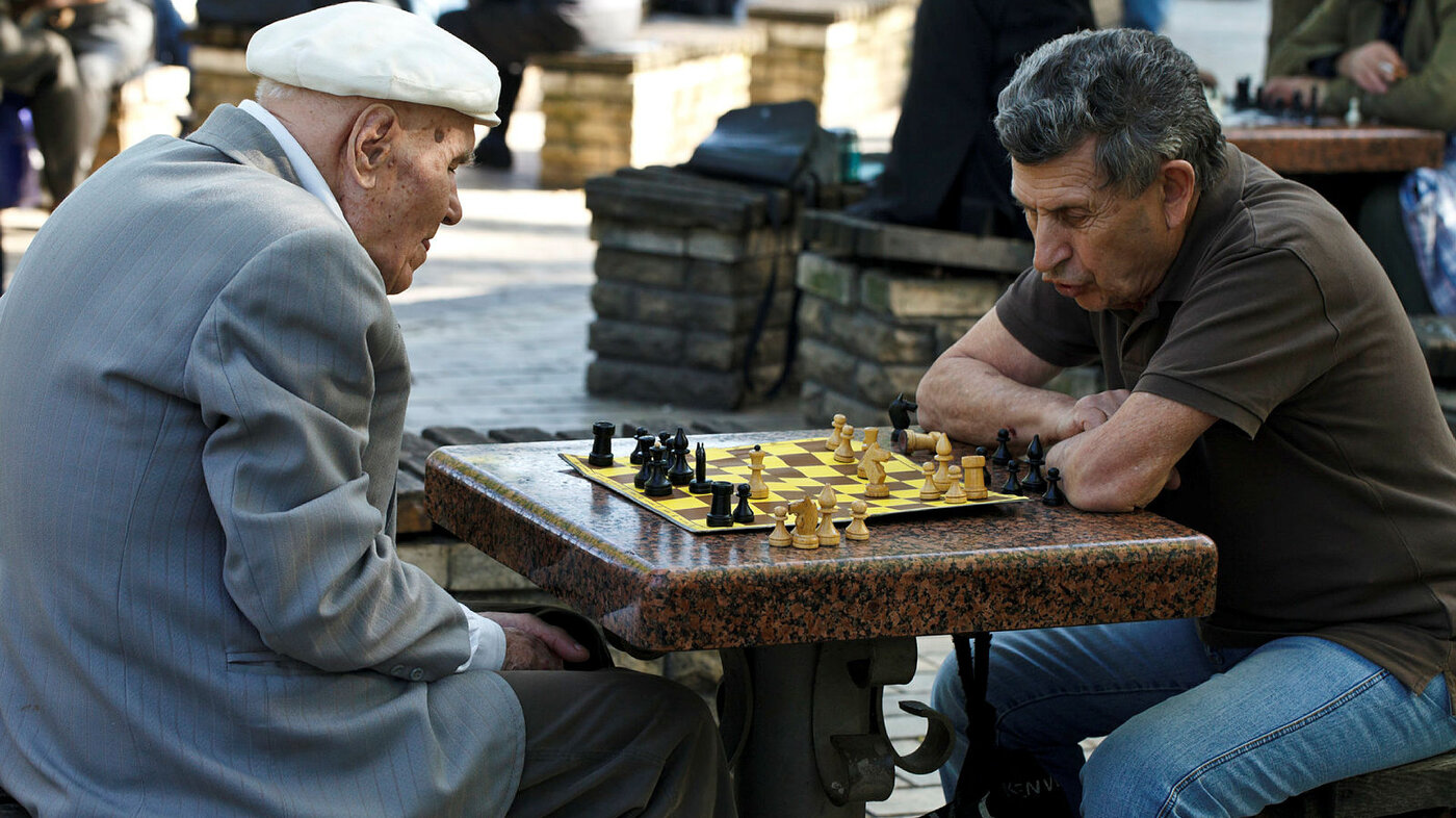 Bildet viser to eldre herrer som spille sjakk i en park