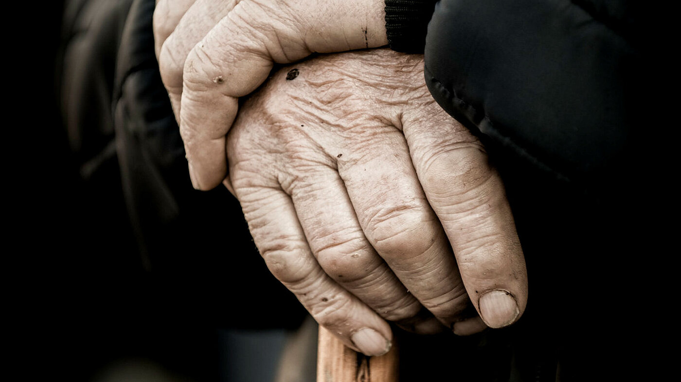 Nærbilde av eldre hender på en stokk