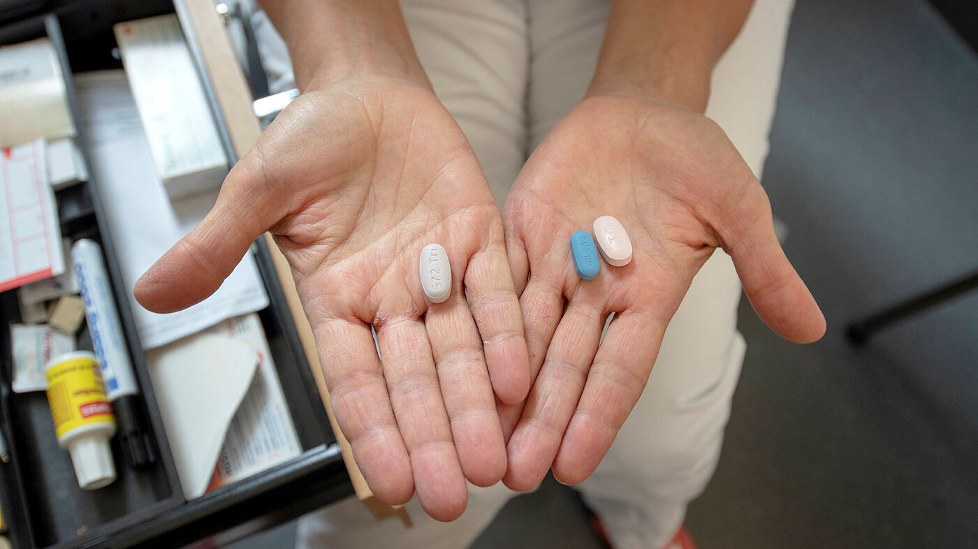 Bildet viser to hender som holder hiv-medisiner.
