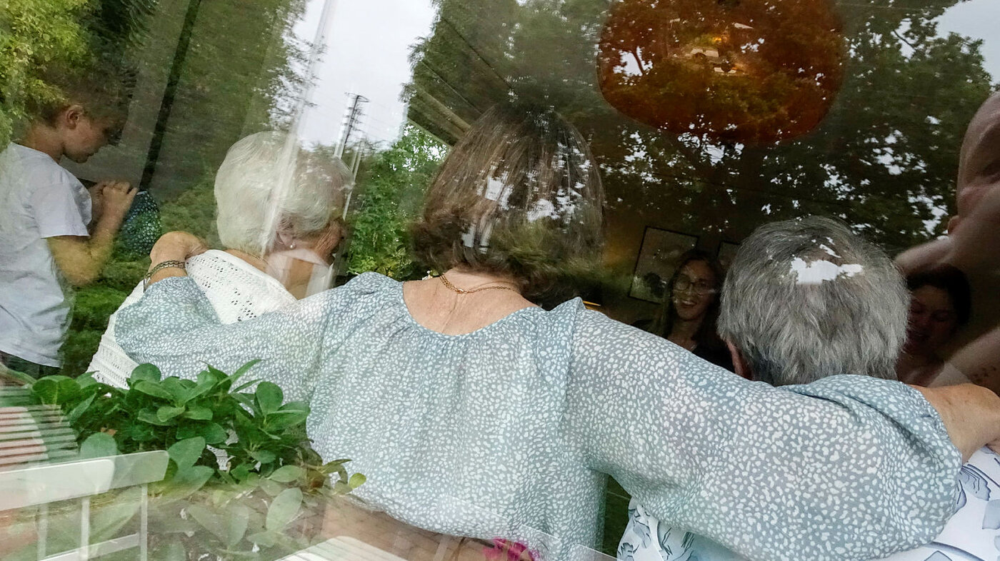 Eldre personer sett bakfra gjennom et vindu.