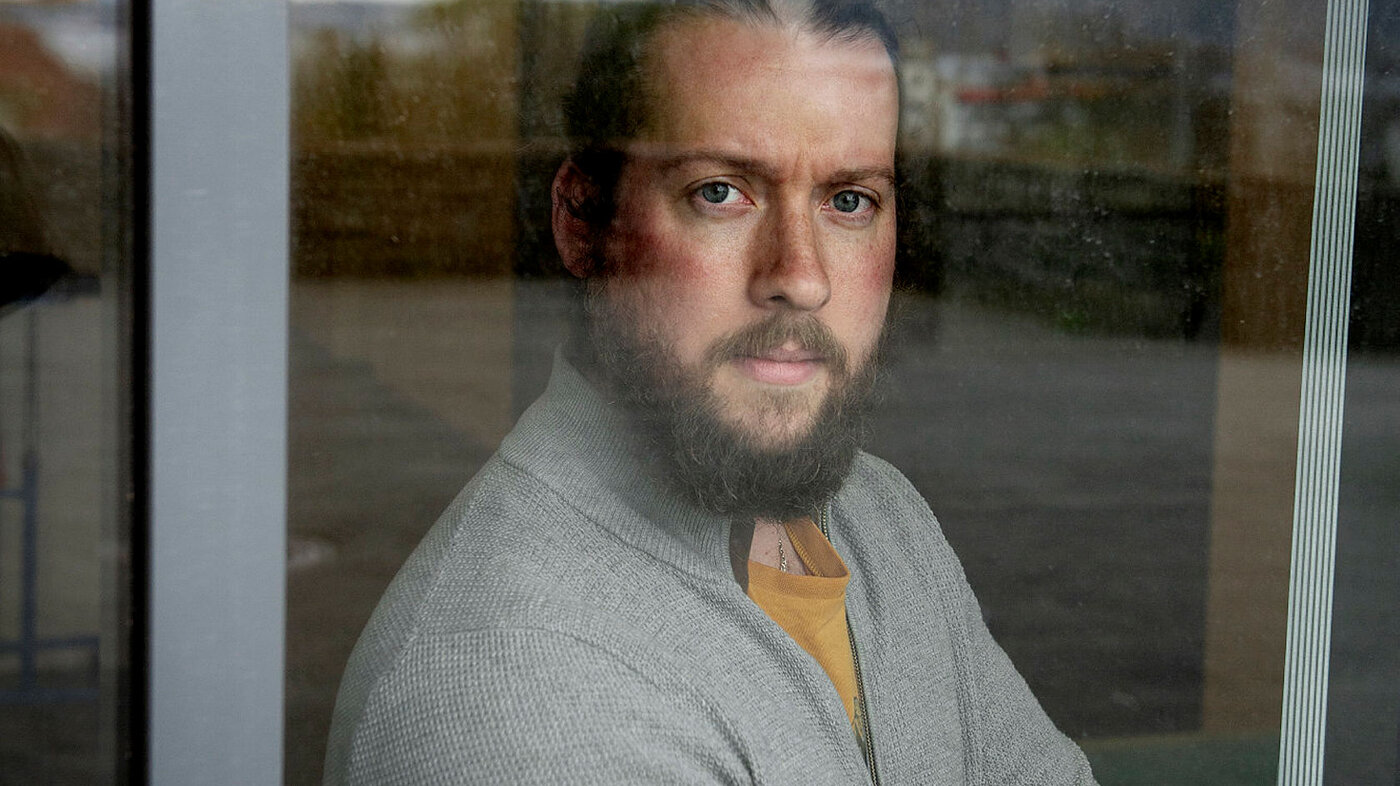 Sykepleier Trond Solholm står bak et vindu ved akuttmottak på Sandviken sykehus.