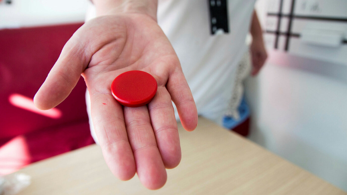 Bildet viser en hånd som holder en rød magnet.