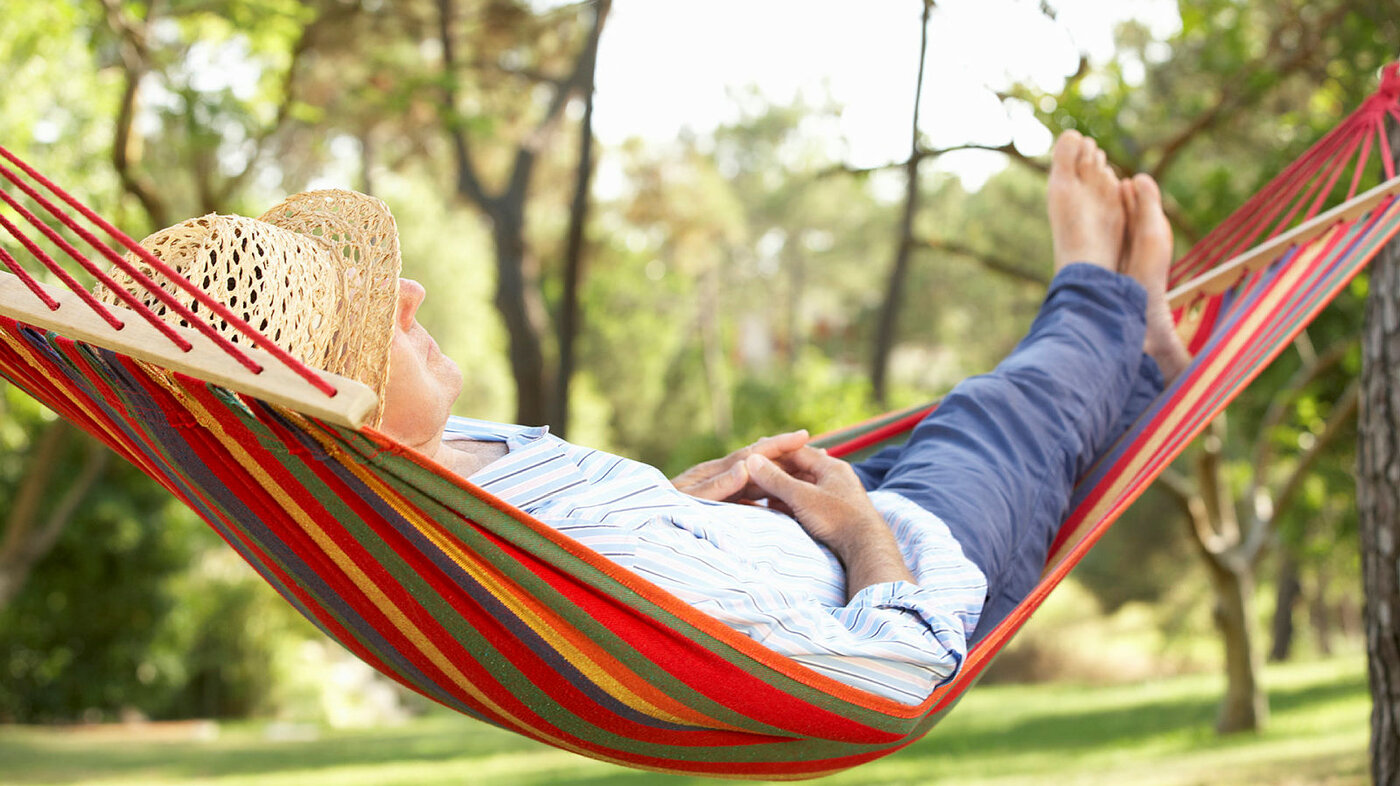 Mann med solhatt som ligger i en hammock