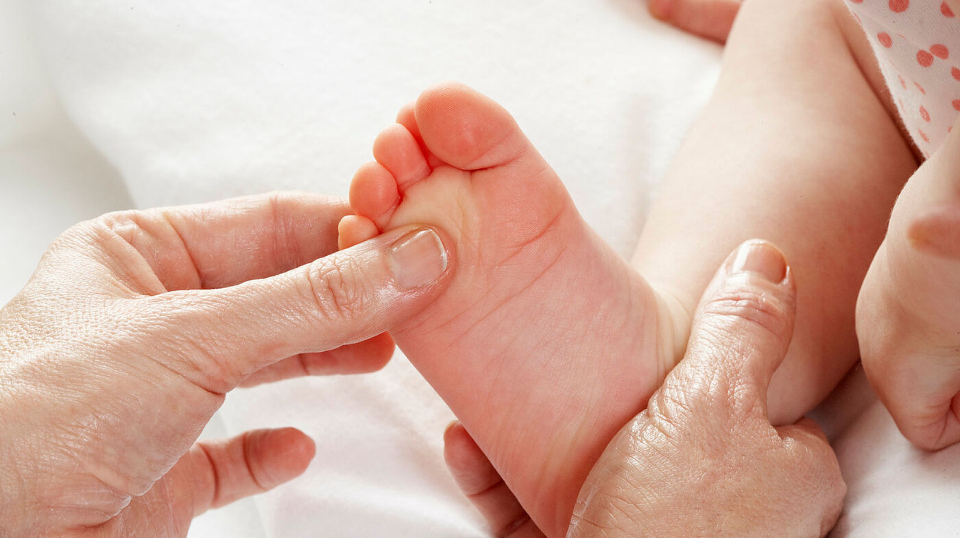 Bildet viser en baby som blir massert på den høyre foten. 