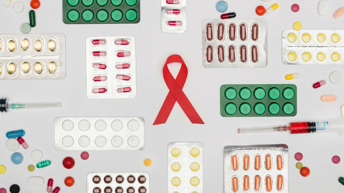 Bildet viser en aidssløyfe omgitt av masse forskjellige typer piller