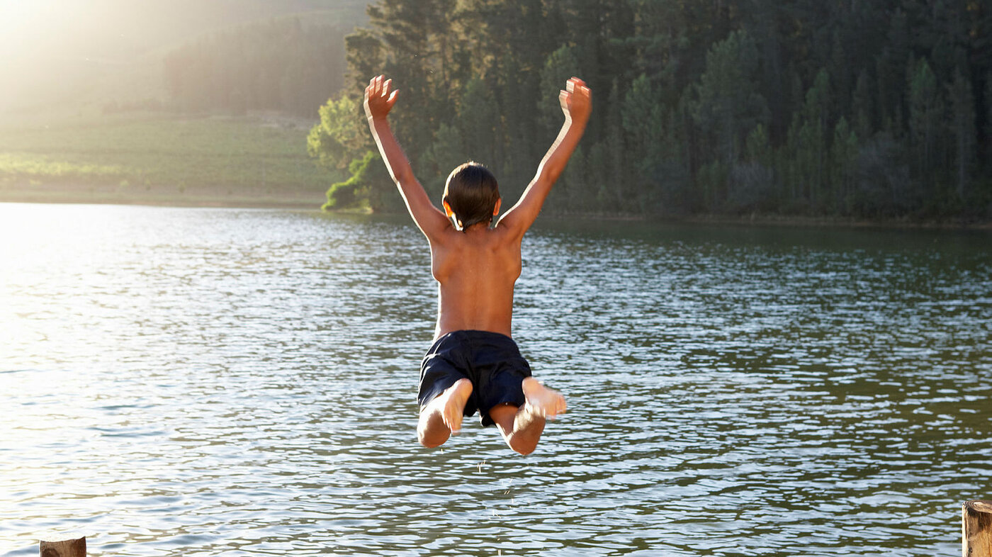 Bildet viser en ung gutt som hopper ut i et vann