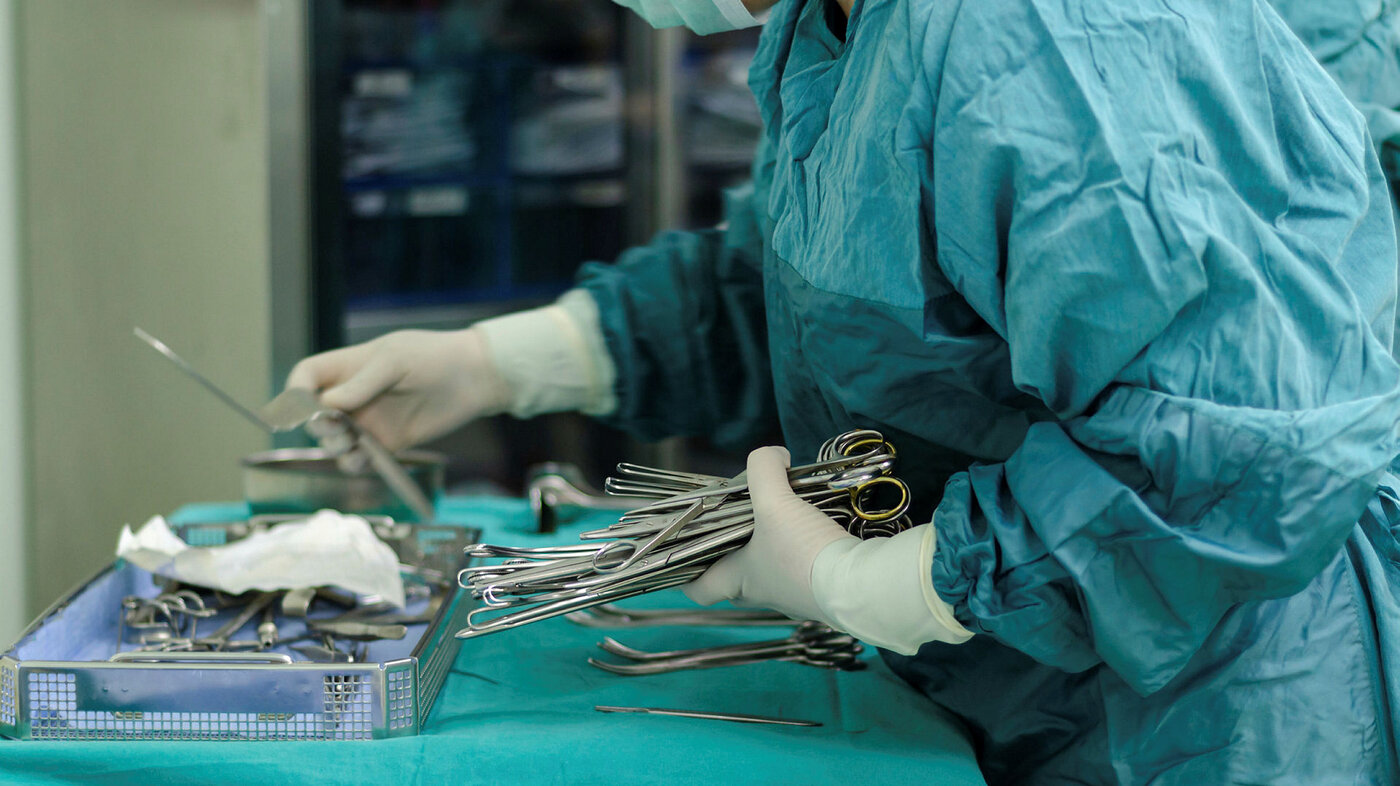 Bildet viser en sykepleier som klargjør instrumentbordet før en operasjon.