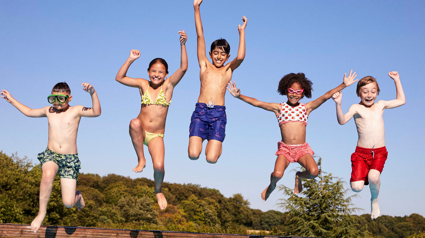 Bildet viser en gjeng med barn som hopper ut i vannet