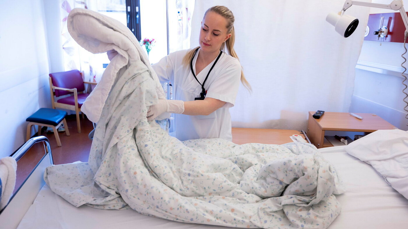 Bildet viser avdelingsvert som rer seng på medisinsk sengepost Sandnessjøen