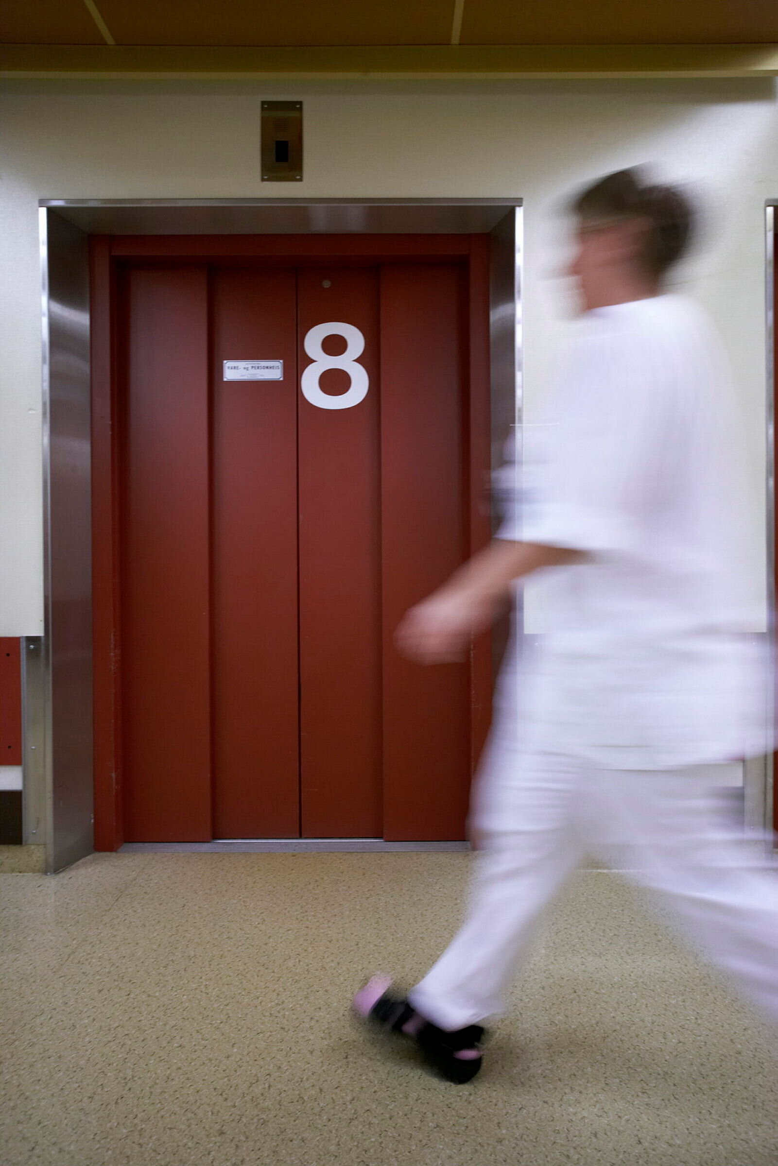 Bildet viser en sykepleier som beveger seg raskt i en korridor Bildet viser en sykepleier som beveger seg raskt i en korridor
