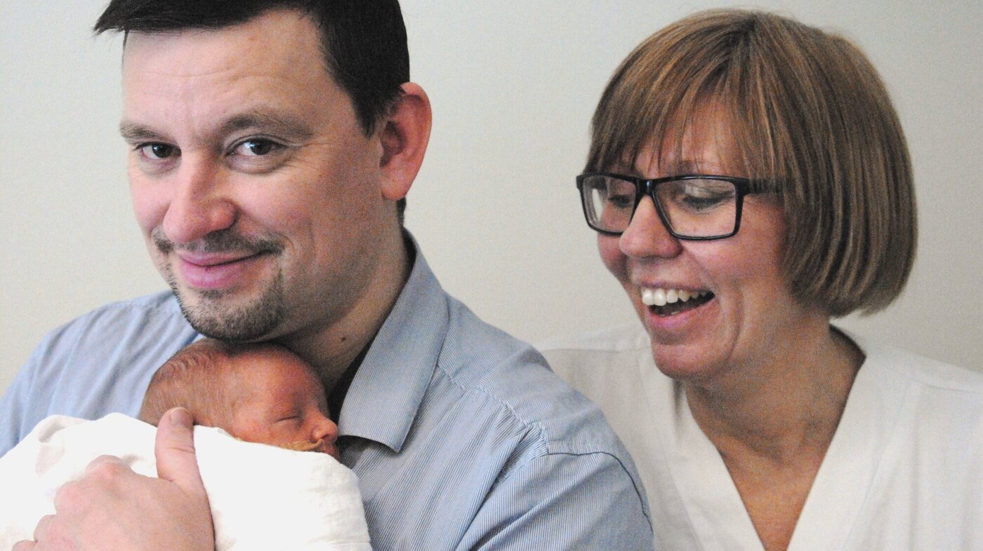 Bildet viser nyfødte Oscar i armene til pappa Alexander Perez, med spesialsykepleier Inger Kopland bak.